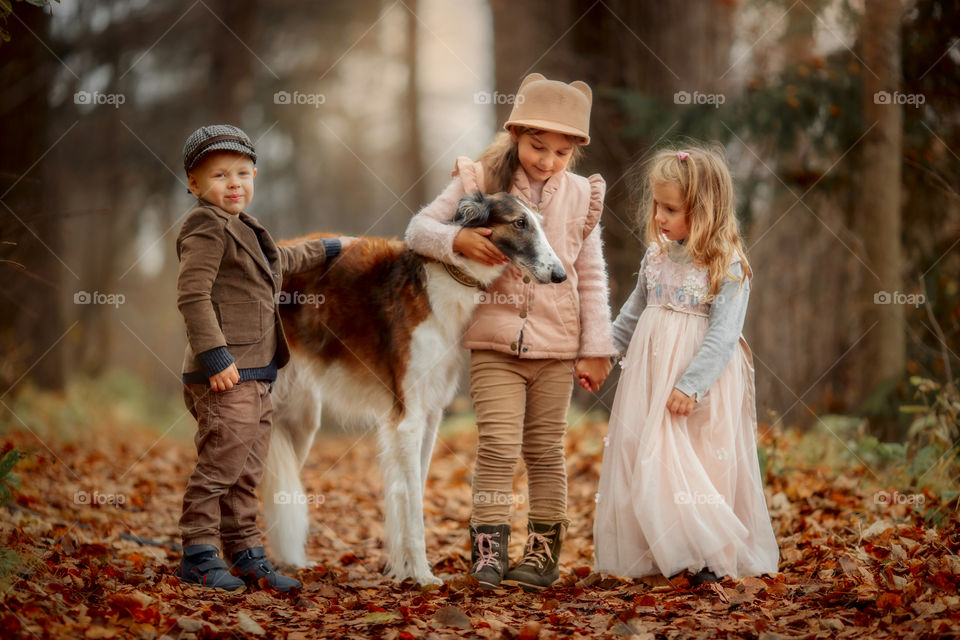 Children with russian borzoi dog in an autumn park 