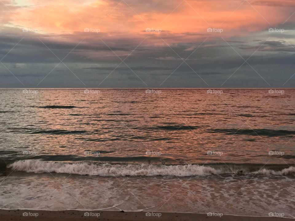 Waves crashing the shore at the beach during the golden hour 