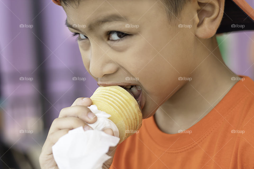 Asian boy holding the ice cream eating.