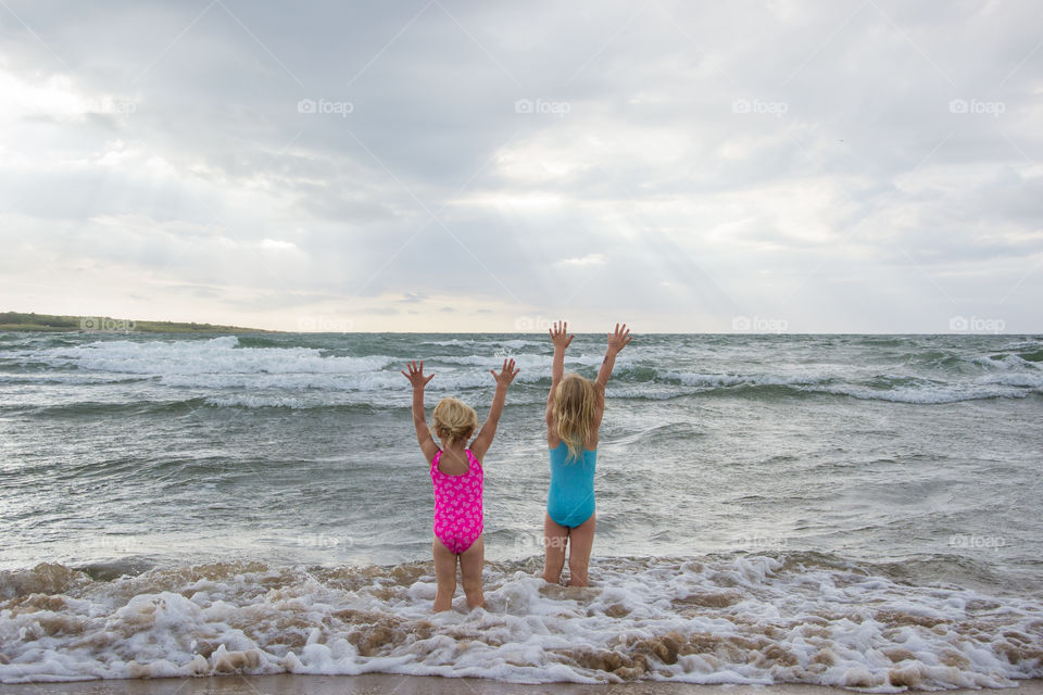 Twi sisters playing at the beach of Tylösand outside Halmstad in Sweden. It's about to get stormy weather but the girls is having fun swimming and playing in the water.