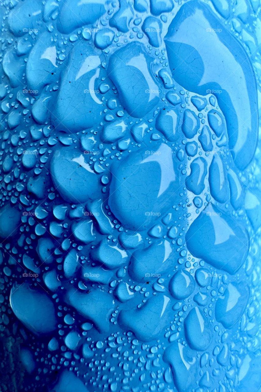 Macro photography of rain drops on blue metallic background 