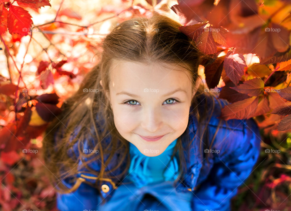 Smiling girl sitting under the autumn tree