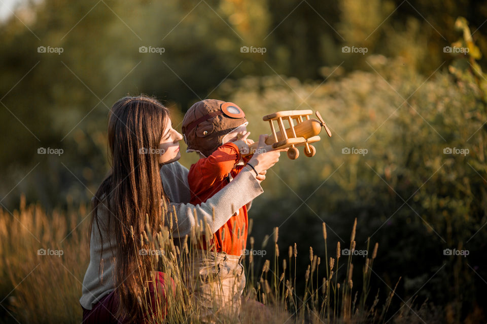 Mother and son with wooden plane at sunset