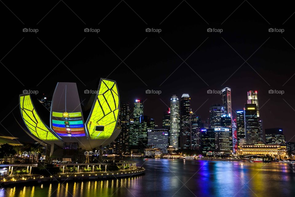 Light display on ArtScience Museum at Marina Bay Sands in the evening in Singapore with the financial district in background