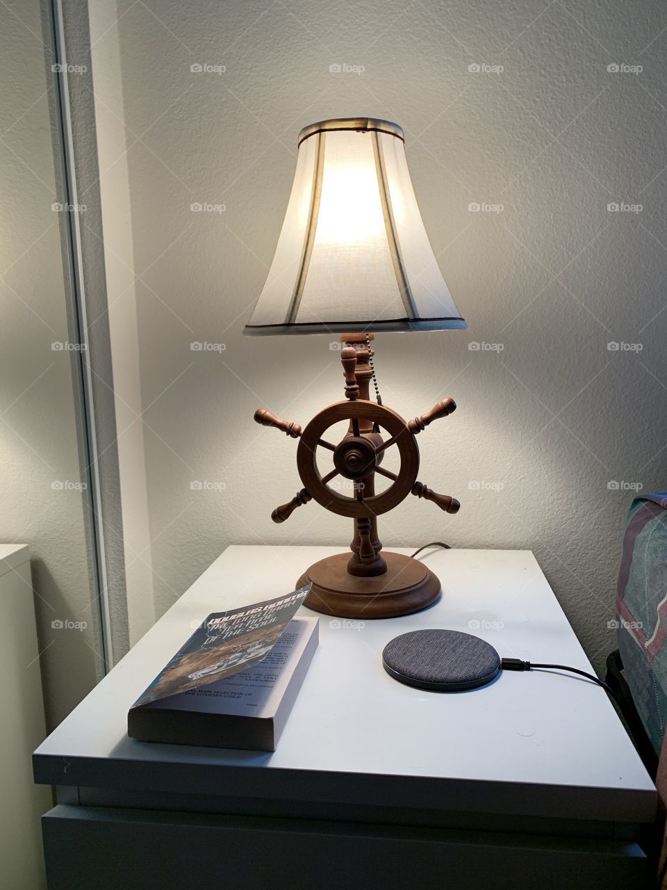 Rustic wheel lamp with wireless charger and book on bedside table. 