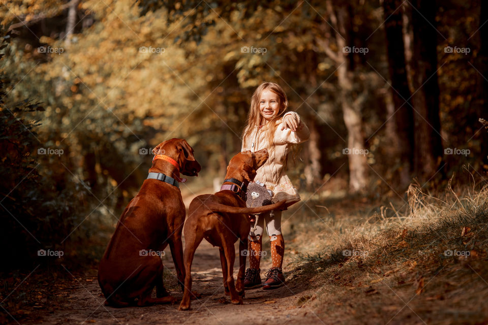 Little girl playing with dogs in an autumn park