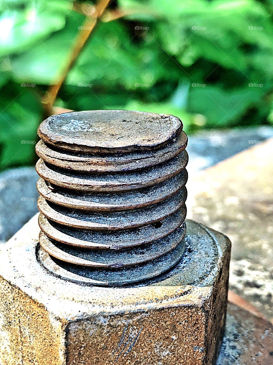 Rusted bolt/screw and nut on a steel structure attached to a concrete block. Rusty texture