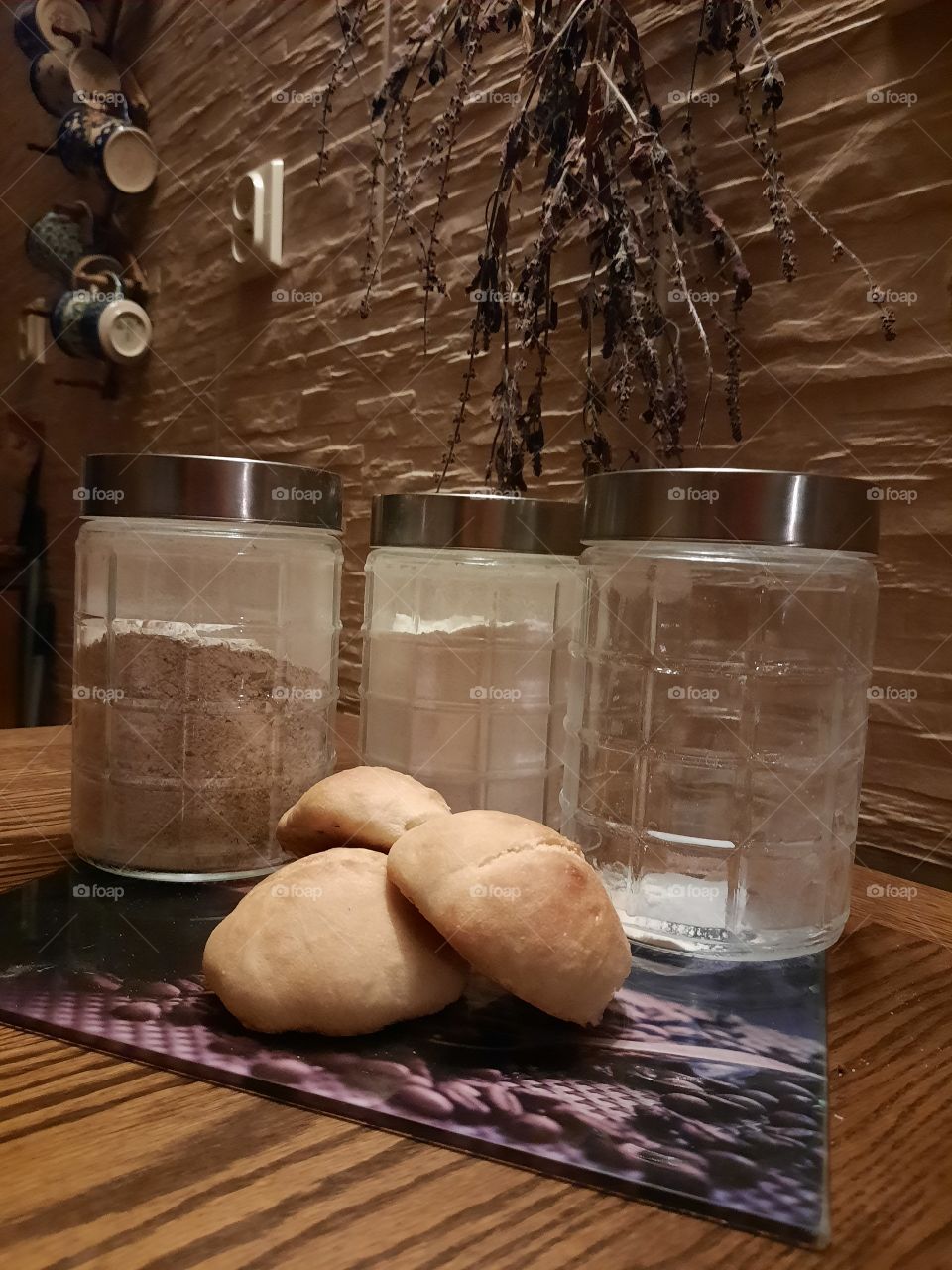 kitchen in early morning - 3 glass pots of flour  and 3 buns  on wooden table