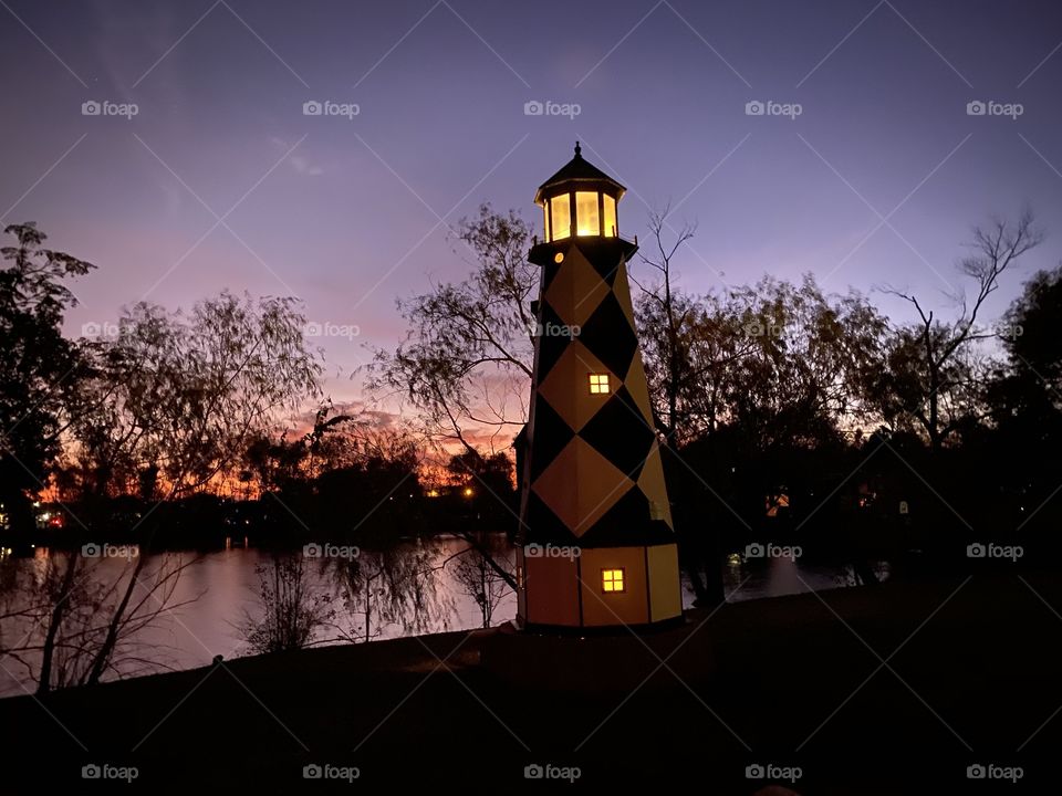 Lighthouse gleaming into the night approach. Backlit lake bed mixing into the twilight making a beautiful setting for sunlight night. 