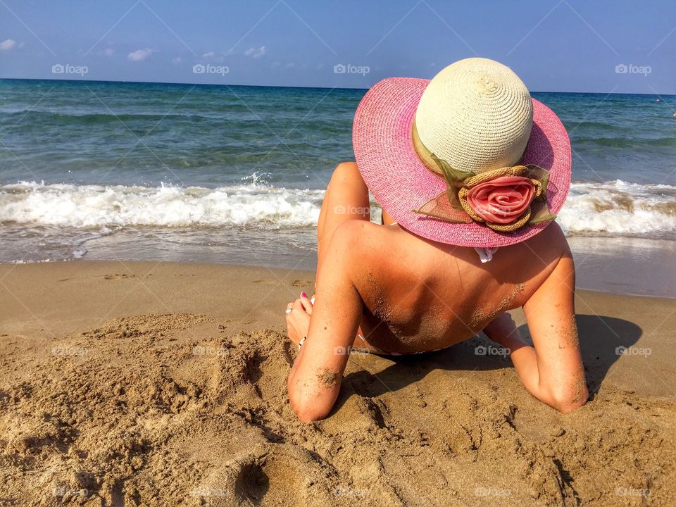 Woman wearing summer hat laying on the beach