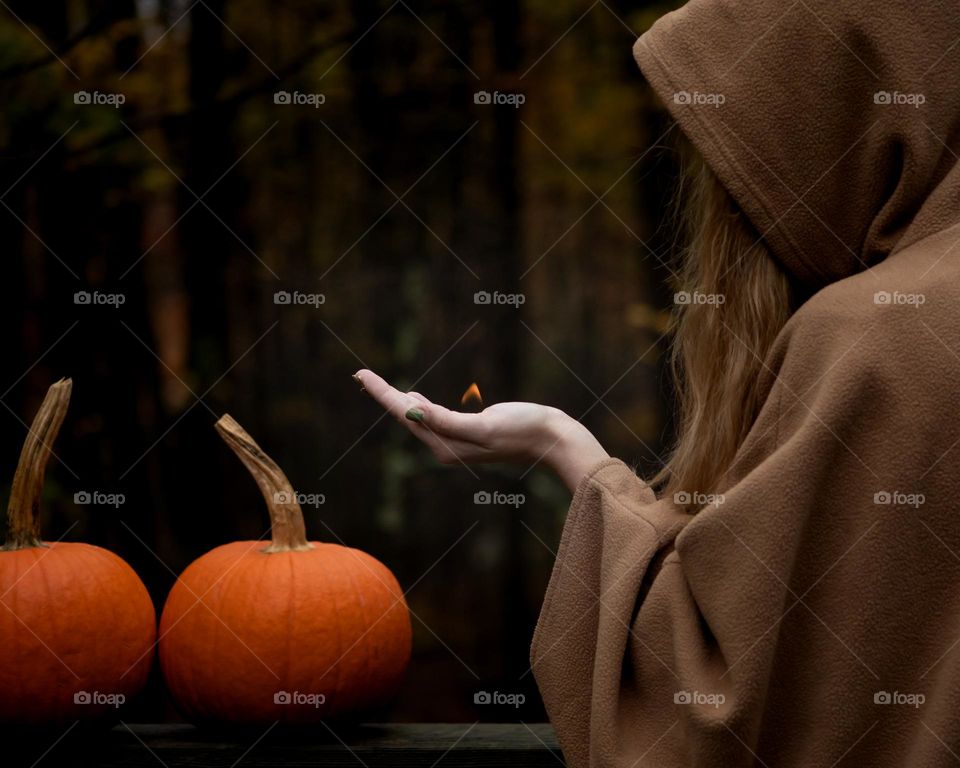 Lighting the Fall spirit; Woman holding a flame to two pumpkins 