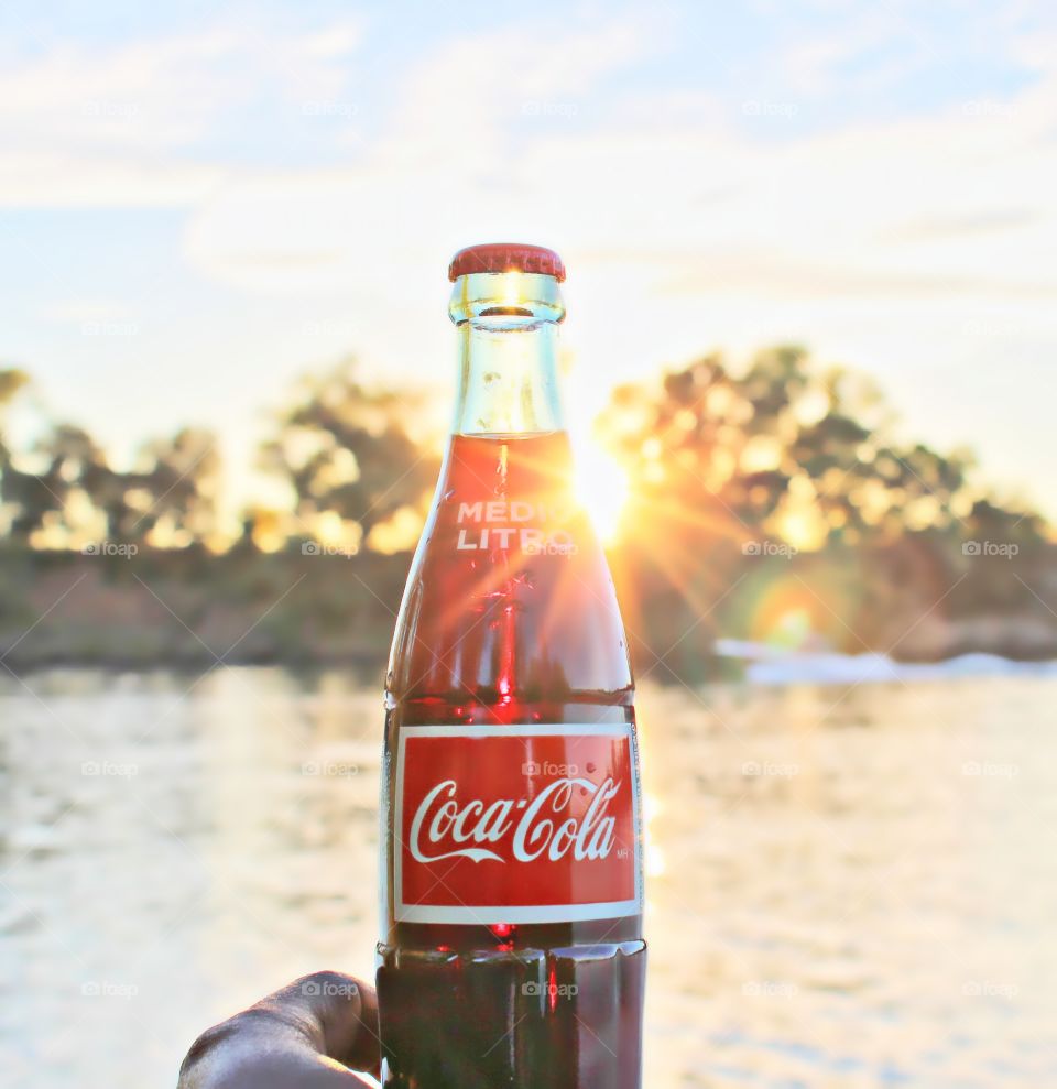 holding a bottle of refreshing Coca-Cola on a sunlit day