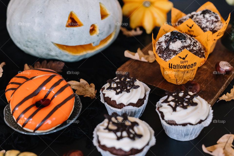 Homemade halloween themed sweets, to be served to children for trick and treat. Chocolate muffins and glazed donuts.