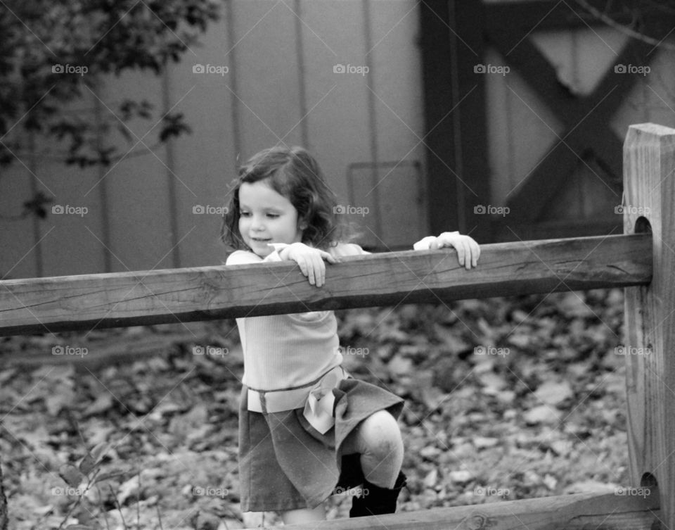Small girl holding wooden railing