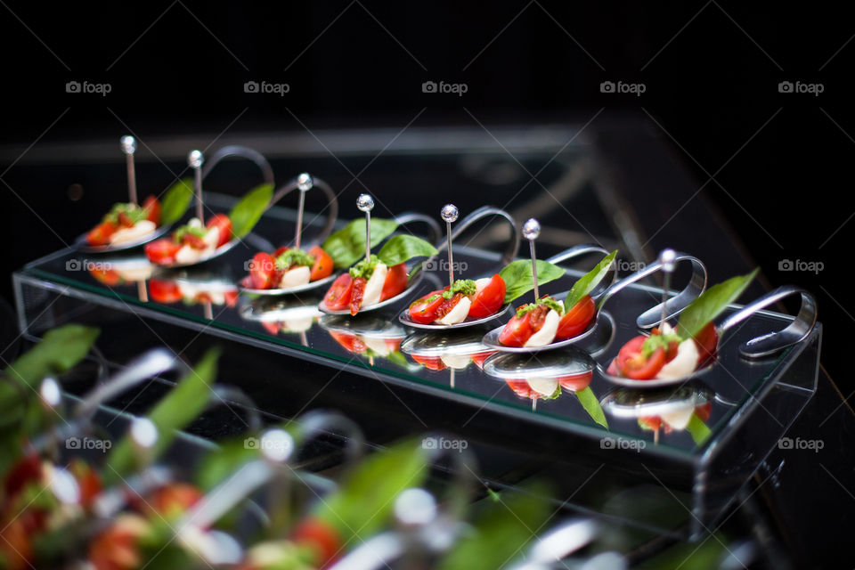 Salad served on spoons with reflection and black background. Close up fresh food.