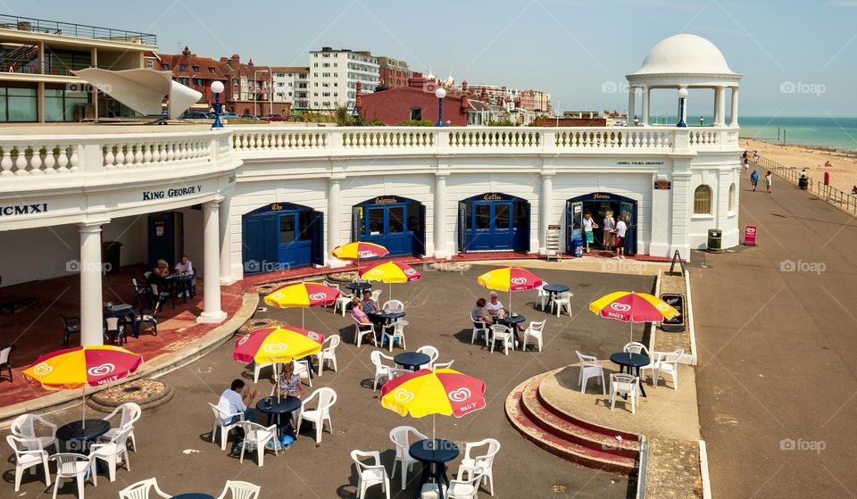 People relax under cafe umbrellas outside the De La Warr Pavilion on Bexhill’s seafront