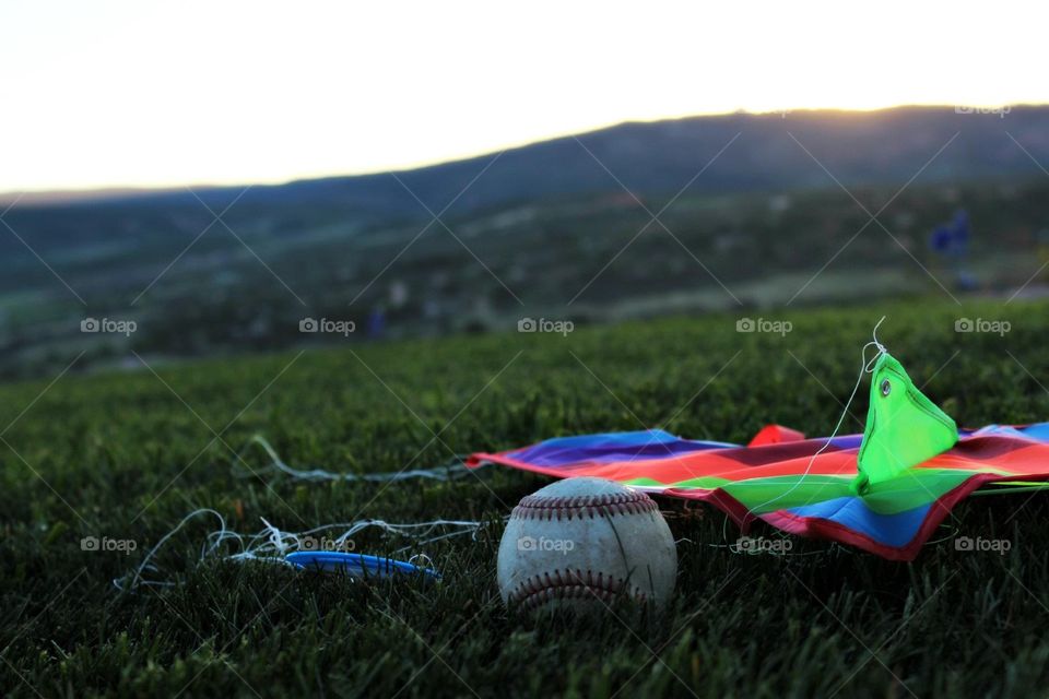 Taken at sunset on a beautiful summer evening, this photograph features a baseball and kite left in the yard after a long day of play. 