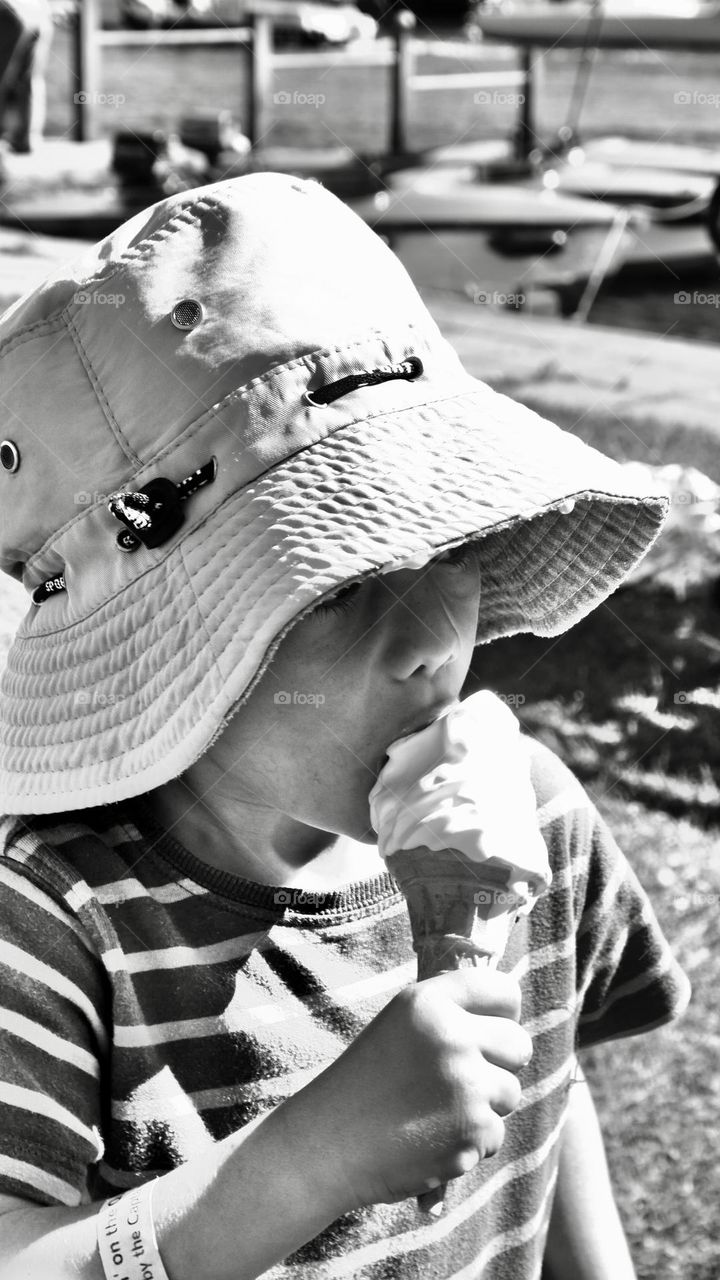 Kid with an hat enjoy his ice cream 