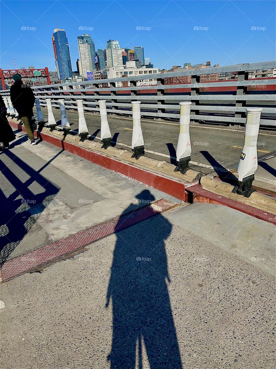 On a sunny day the shadows cast on the “Pulaski Bridge” at “Newtown Creek” that connects “Greenpoint”, Bklyn to LIC, Queens can be quite amazing such as this elongated slightly warped imprint of myself, the photographer. 2023. Hypnotic Productions