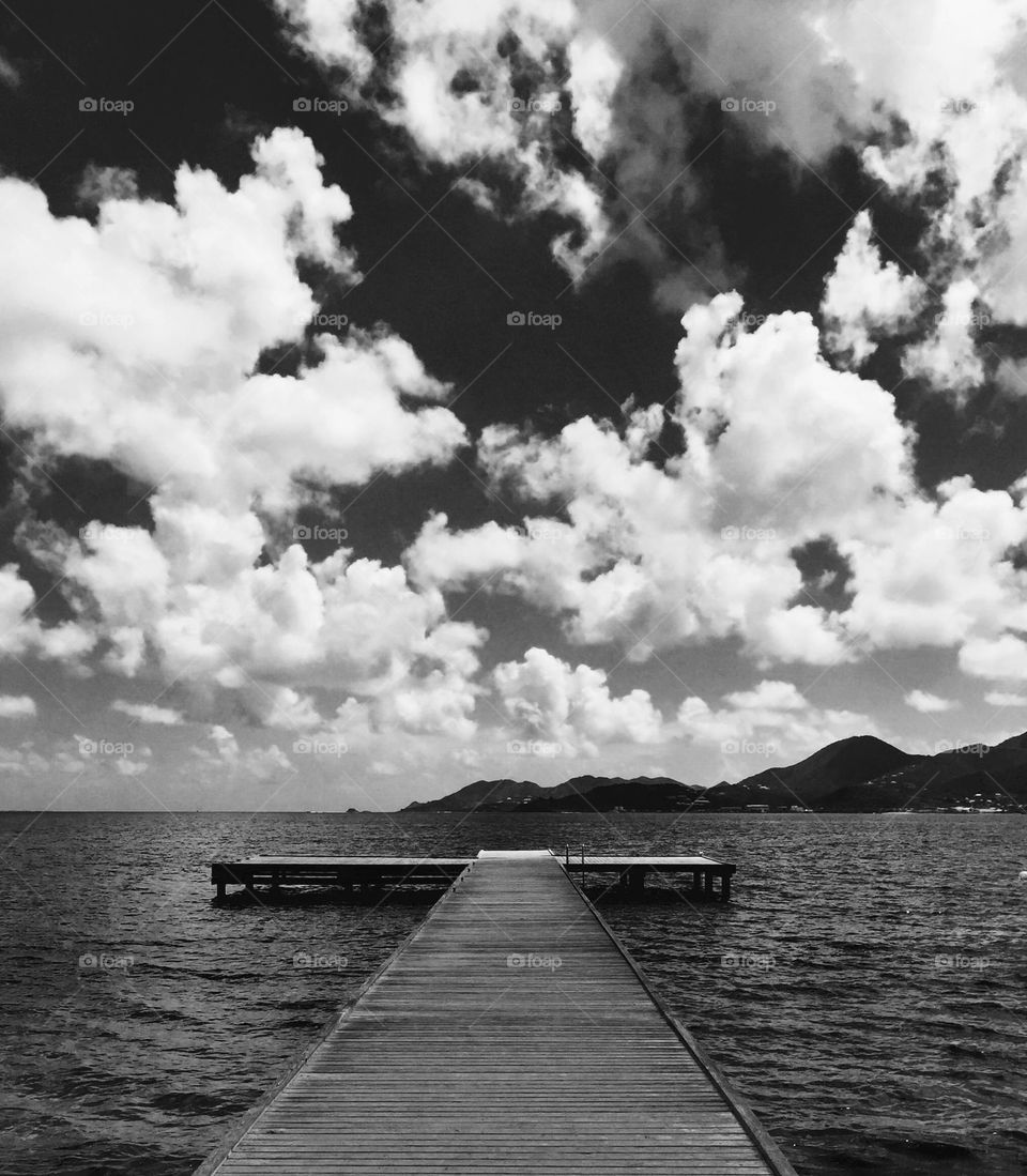 Black and white pier image, pier on Caribbean island, St. Martin beaches, clouds in the sky, sky meets water 