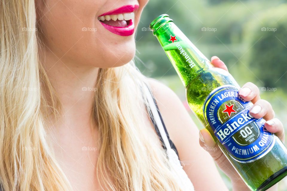 Happy woman having a cold none alcoholic Heineken beer 