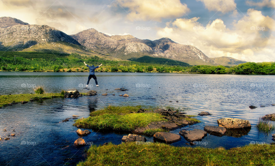 Man jumping in the air with mountains in the at Lough Inagh in Connemara National park, county Galway, Ireland