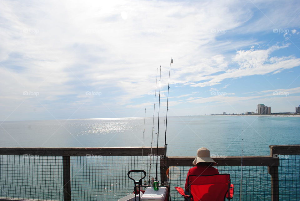 An elderly woman fishing at the pier