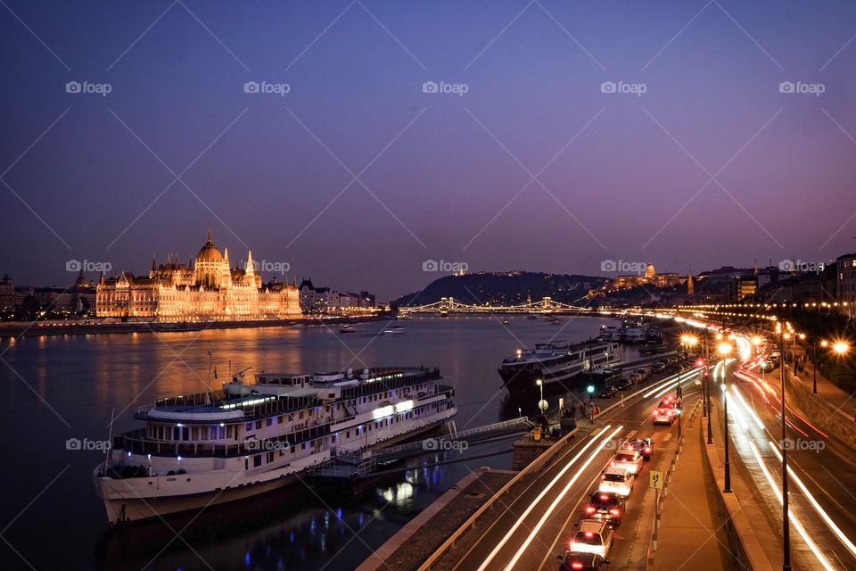 Fine evening in Hungary’s Budapest with the scenery of the Hungarian Parliament Building, Danube River, cruises, boats, and city traffic 