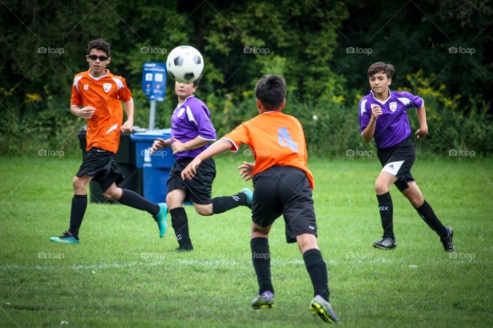 Teens are playing soccer outdoors