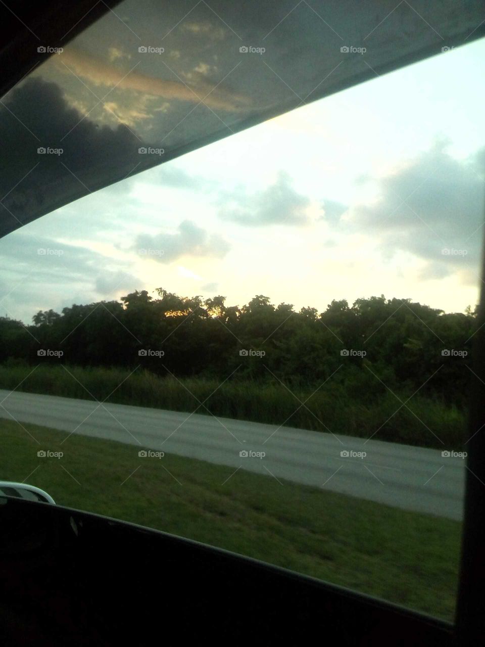 this picture was taken from a car window that  was  drive in looking how beautiful the sun set is
