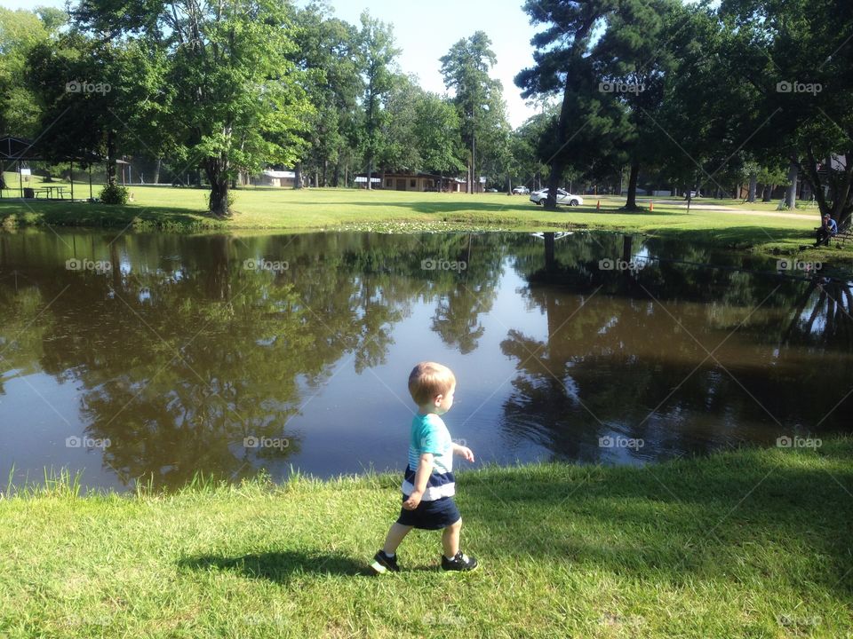 Boy walking around pond