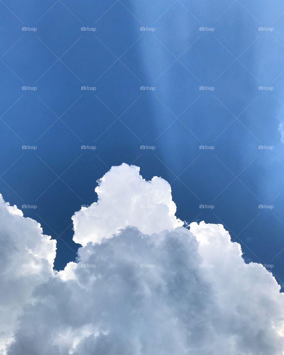 Sun rays peeking through the clouds in the brilliant blue sky.