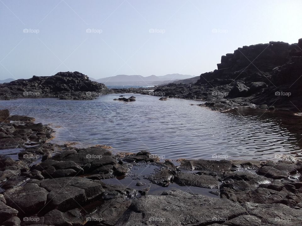 A natural swimming pool among rocks in a very wild coast. The Atlantic ocean as natural background