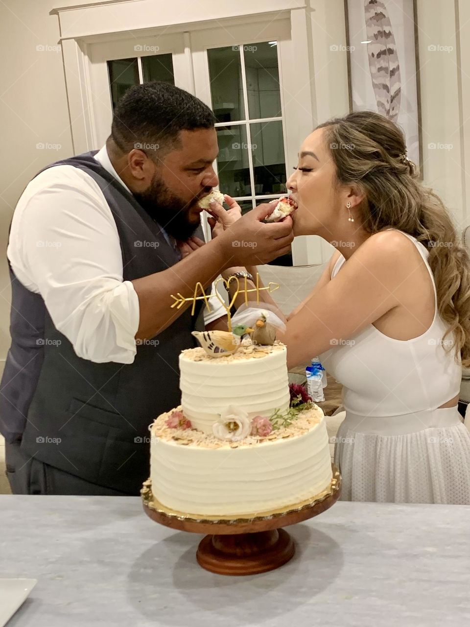 The bride and groom feeding each other a small piece of cake. This romantic and sweet gesture symbolizes the commitment the couple has made to provide for one another and it is a display of affection and love between the two.