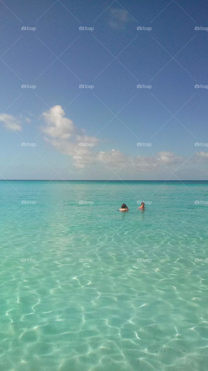 A couple enjoying the Clearest blue ocean in Belize. beautiful light reflections in the water and few clouds in the sky. 