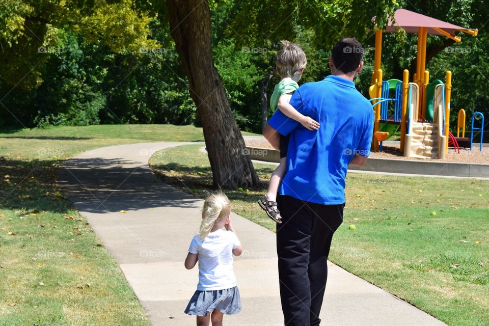 A father taking his son and daughter to the park to play