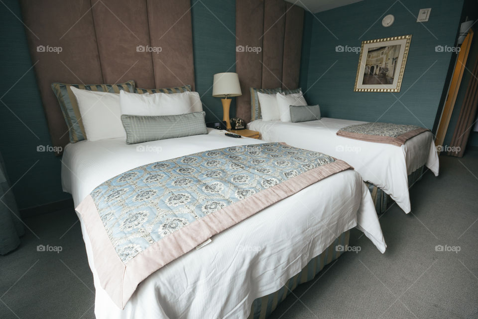 Two made up queen beds in a fancy hotel 