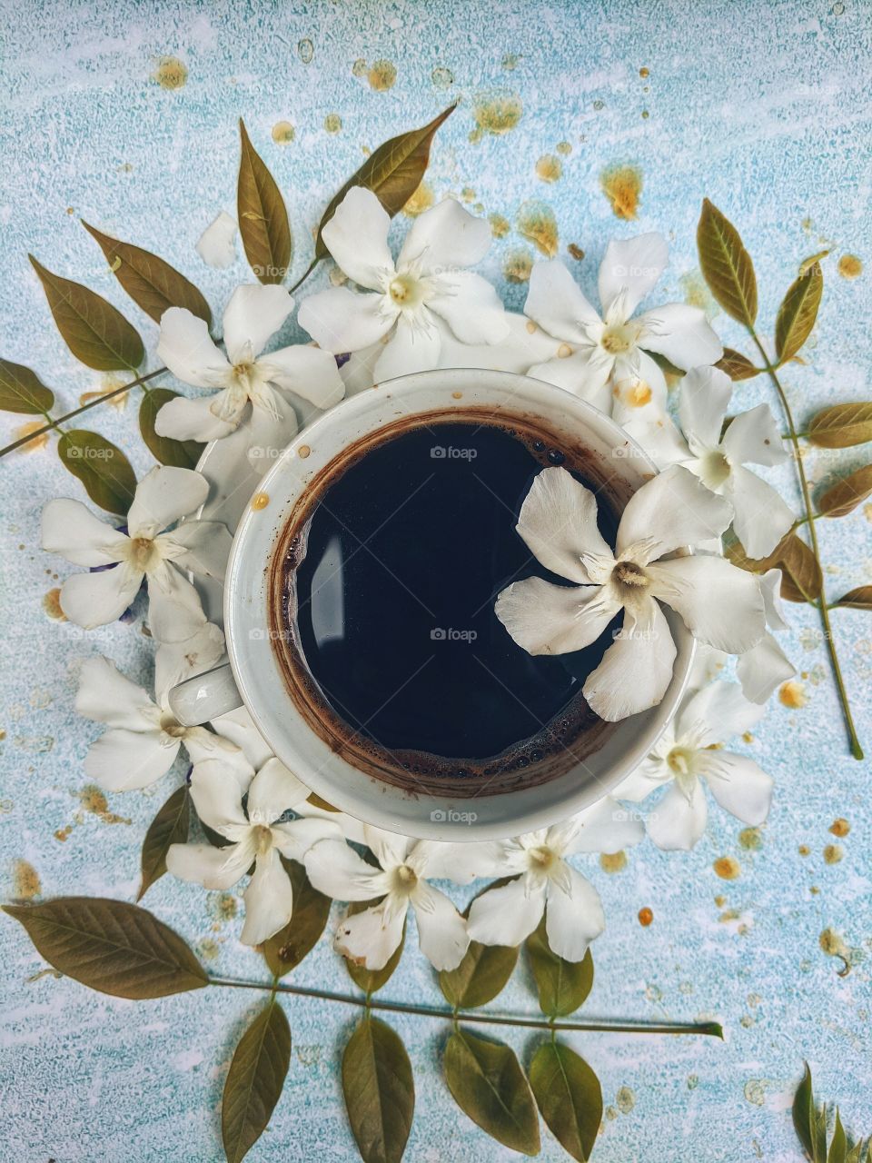 Background of a cup of hot coffee on the table with beautiful flowers close-up. Top view.
