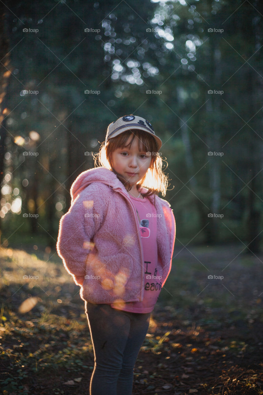 Little girl in evening forest. 