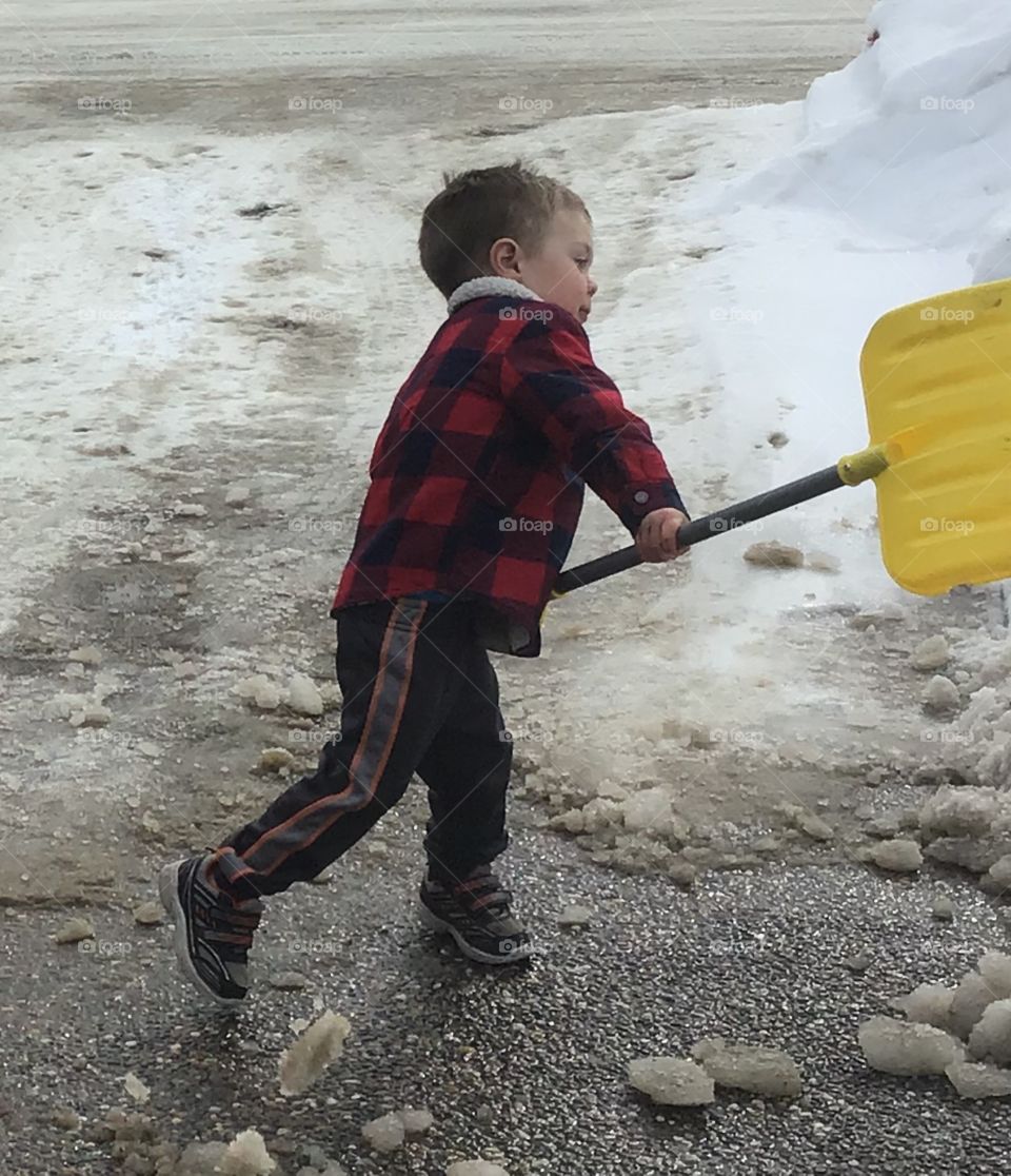 Little boy shoveling the driveway