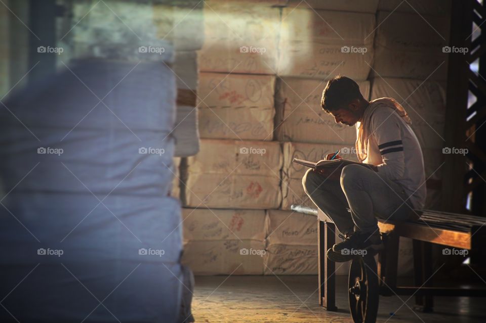 A man writes in his journal at a train station.