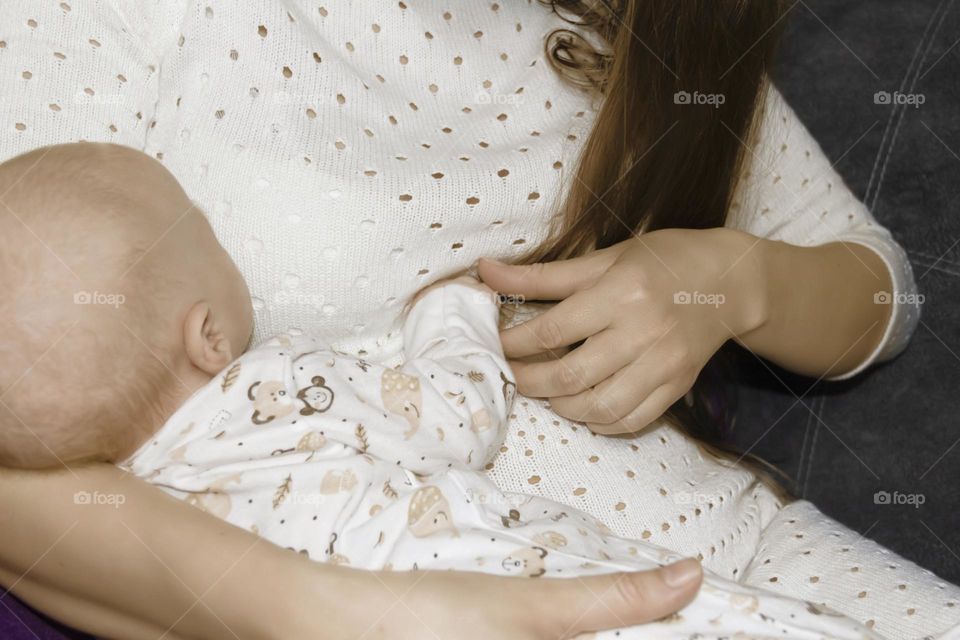 A happy mother is holding and breastfeeding a newborn baby. Lifestyle and newborn.