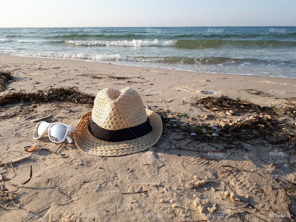 Straw hat and white sunglasses at the beach each