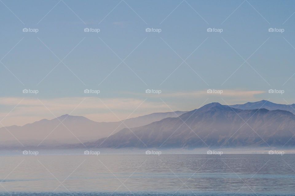 Mountain range seen in the distance across the Salton Sea in Riverside and Imperial counties, with the mist rising off the water giving a watercolor effect 