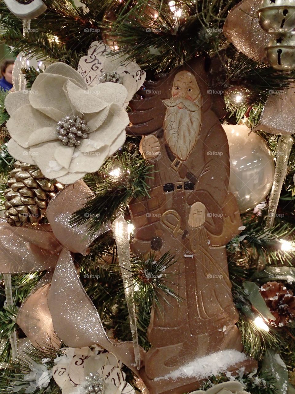 An old traditional ceramic Santa Claus ornament hangs from a lighted Christmas tree. 