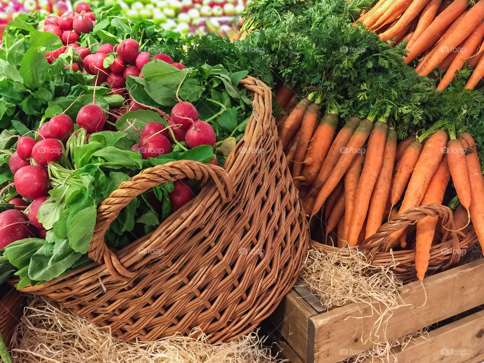 Fresh harvested organically grown vegetables stacked in market stall ready for sale at farmers market.