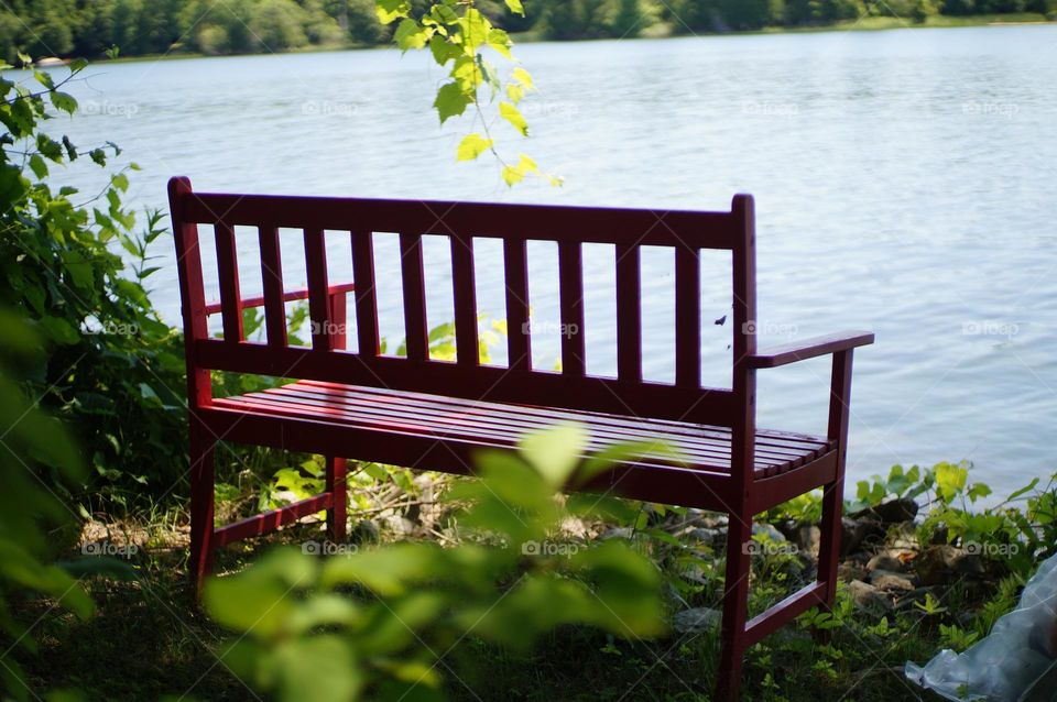 Peaceful red bench by the lake.