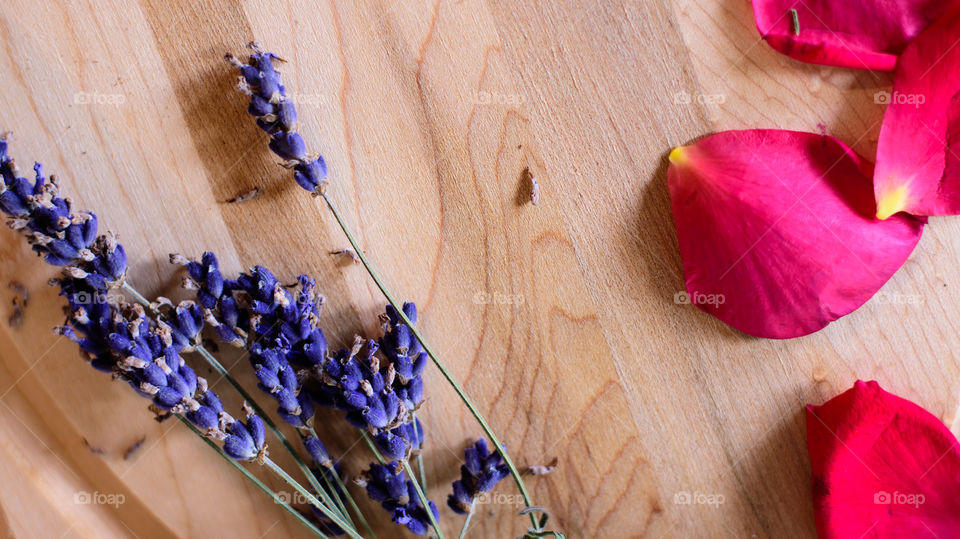 Flat lay of fresh lavender flowers and red rose petals on wood background aromatic edible flower ingredients or beauty fragrance and skincare ingredient summer flower background with room for copy 