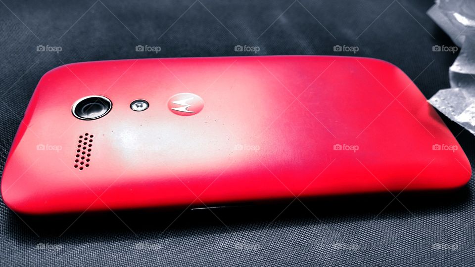 Celular Motorola com capa vermelha.