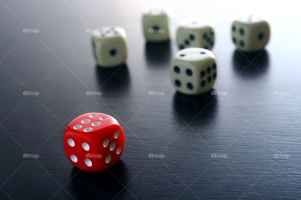 red game dice. 1 red game dice in front of 5 white game dice